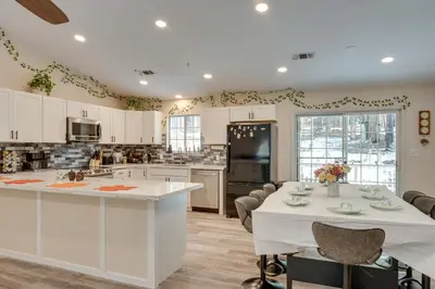 a kitchen with white cabinets and a table with chairs at Renovated Pioneer Home in Serene Wooded Setting! in Pioneer