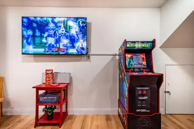 a room with two arcade games and a television on a wall at Red Rock Falls Cabin, 8 miles from Yosemite South Gate, with trailhead, Game Room and HotTub in Oakhurst