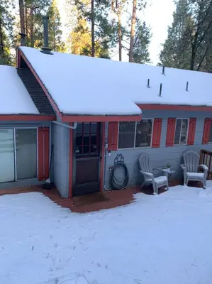 a house with snow on the roof and two chairs at Harte's Desire Cabin - Lake, A/C, Arcade + in Twain Harte