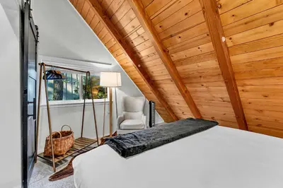 a bedroom with a white bed and a chair at The Rigi Chalet HOA Beach Access Close to town in Tahoe City