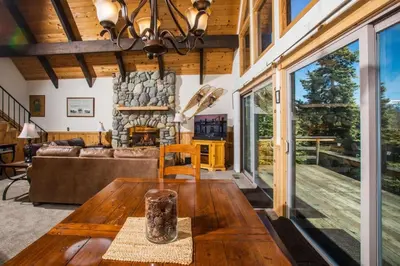 a living room with a wooden table and a fireplace at Carnelian Bay View Cabin in Carnelian Bay
