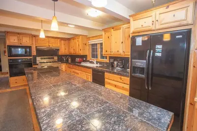 a kitchen with wooden cabinets and a black refrigerator at The Tallac Lodge Hot Tub Walk 2 Beach in Carnelian Bay