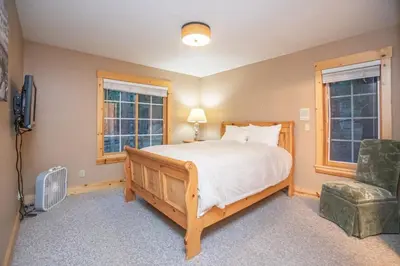 a bedroom with a bed and a chair and windows at The Tallac Lodge Hot Tub Walk 2 Beach in Carnelian Bay