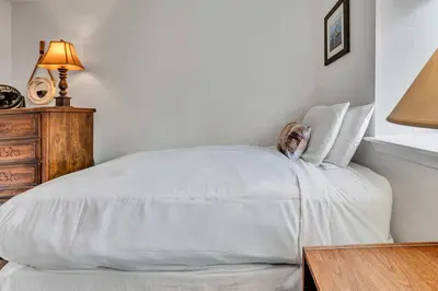 a bedroom with a white bed with a lamp and a table at Modern 3BD -Walk to Lake & Beach in Tahoe City