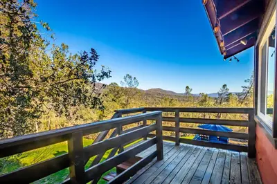 a view from the porch of a house with a wooden railing at Sierra Vista Lookout Lodge with Creek, Waterfall and Waterholes, minutes from Bass Lake and Yosemite South Gate in North Fork