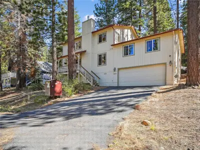 a house with a garage in the woods at High Sierra Escape - Cozy, Spacious Mountain Home in South Lake Tahoe
