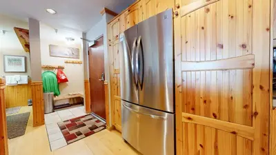 a kitchen with a stainless steel refrigerator and wooden walls at Aspen Creek #227 condo in Mammoth Lakes