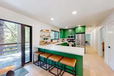 a kitchen with green cabinets and a counter with stools at Piney Point in Arnold