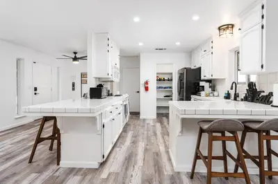 a white kitchen with white cabinets and wooden floors at Country Club Hideout - w/ HotTub, King bed in Oakhurst