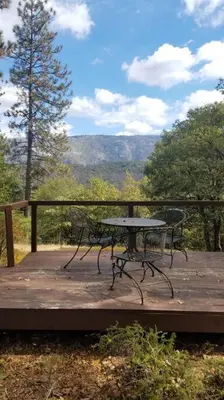 a picnic table on a deck with a view of the mountains at Uncle Grizz's Cabin...get intouch with nature in Bass Lake Annex