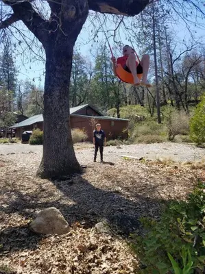 a man standing next to a tree with a person in a swing at Uncle Grizz's Cabin...get intouch with nature in Bass Lake Annex